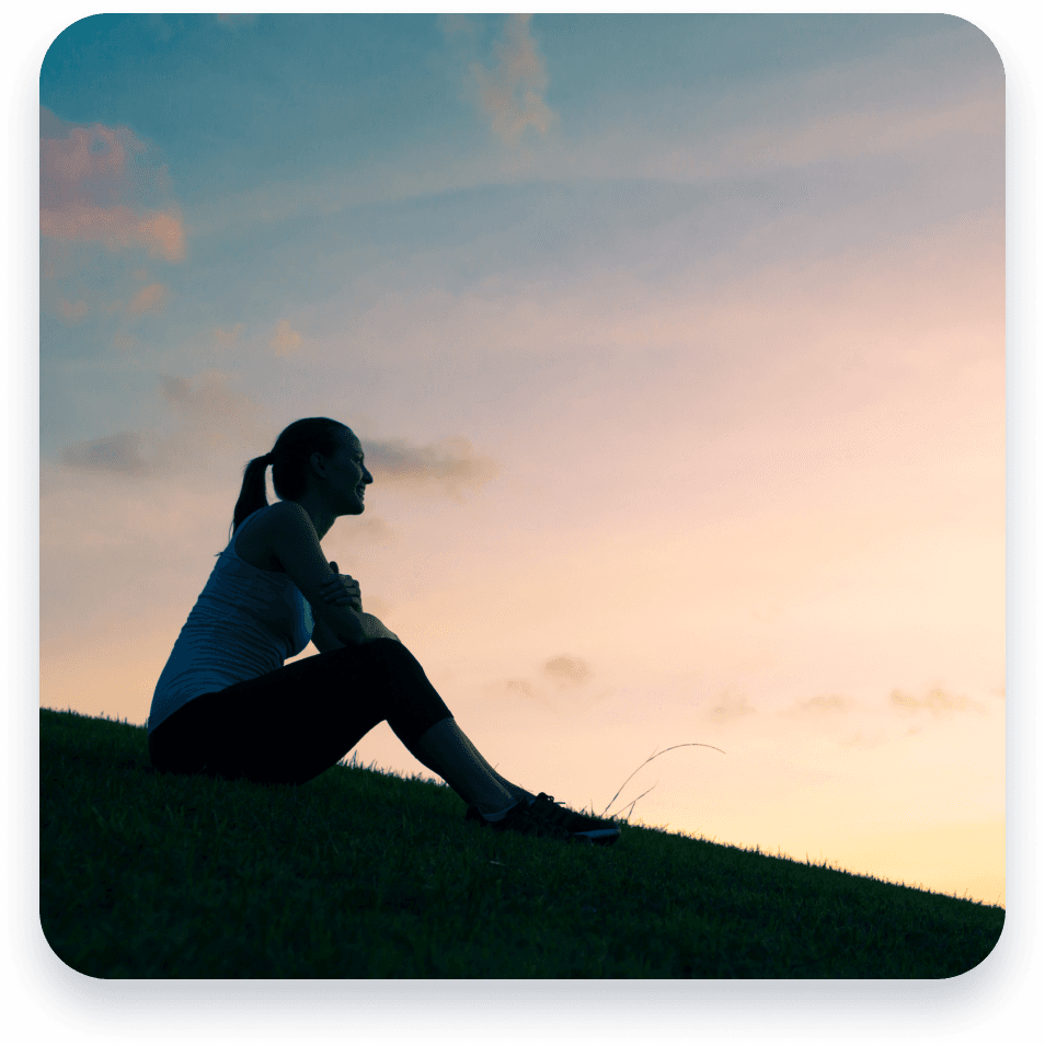 A woman sitting on a hill looking into the distance.
