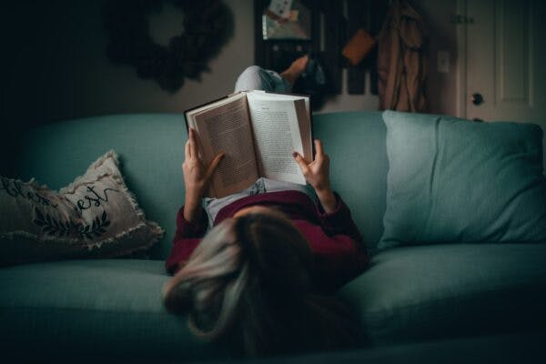 Person reading a book on a couch